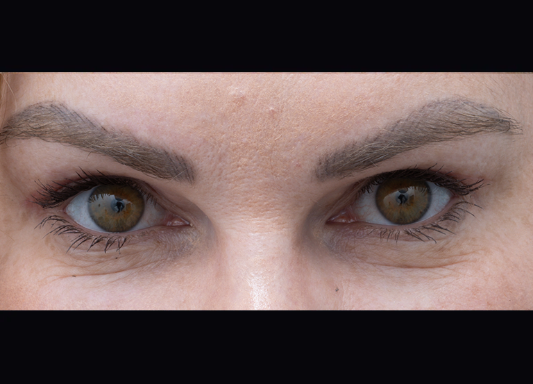 Close-up of a person's eyes with hazel-brown irises and well-groomed eyebrows, seen from the front.