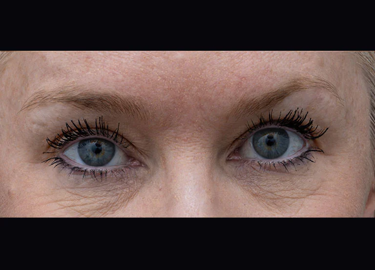 Close-up of a woman's blue eyes with mascara and eyeliner, looking straight ahead.