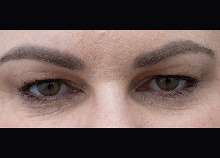 Close-up of a woman's eyes with brown irises, mascara, and groomed eyebrows.