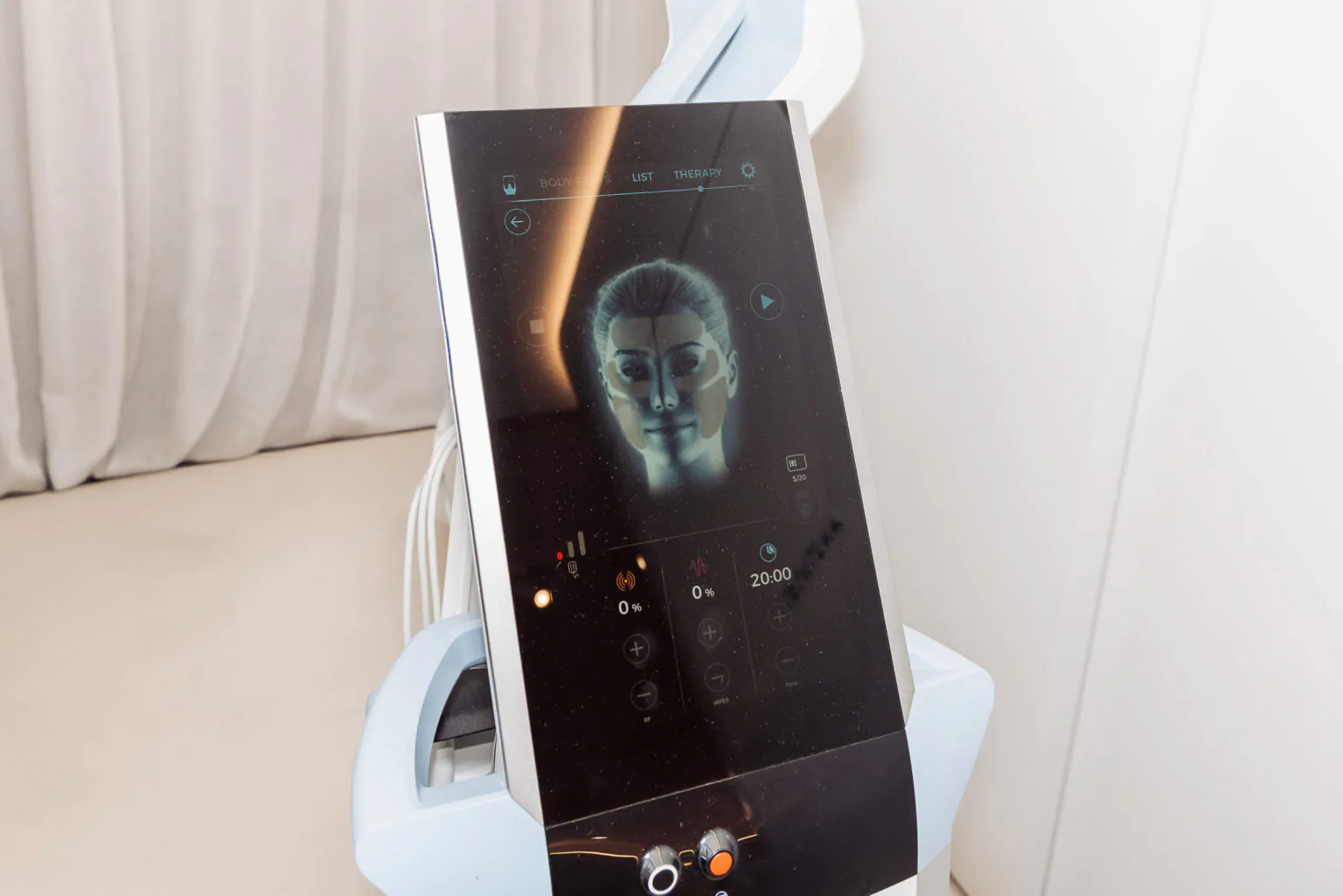 Touchscreen on a medical device showing a digital human face and control icons